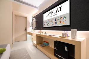 a living room with a flat screen tv on a wall at Layflat Hotel in Shenzhen