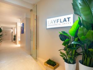 a hallway with plants and a sign on the wall at Layflat Hotel in Shenzhen