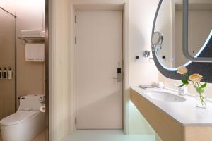 a bathroom with a sink and a mirror and a toilet at Layflat Hotel in Shenzhen