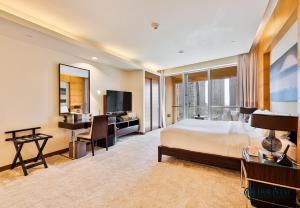 ein Schlafzimmer mit einem Bett, einem Schreibtisch und einem Fernseher in der Unterkunft Kempinski Central Avenue Residence - Direct Access Dubai Mall in Dubai
