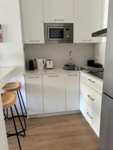 a white kitchen with white cabinets and a microwave at Casa Dalia - One bedroom flat in Torremolinos