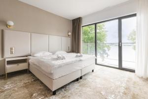 a bedroom with a large bed and a large window at Blue&Green Masurian Hotel in Węgorzewo
