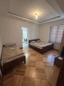 a bedroom with two beds and a wooden floor at Apartmani prenj 1 i 2 centar in Konjic