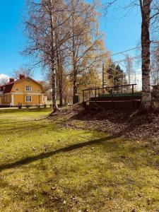 a field with a house and trees in front at Majatalo Mäntän Kuusela in Mänttä