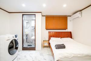ein Schlafzimmer mit einem Bett und einer Waschmaschine in der Unterkunft 5BR Family House, Myeongdong 7 minutes, Gwanghwamun 10 minutes, Namsan view, Patio in Seoul