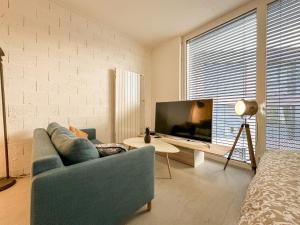 a living room with a blue couch and a tv at Studio 20 in Le Mont-sur-Lausanne