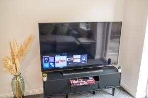 a flat screen tv sitting on a black entertainment center at House Sleeps6-Garden-PetsOk-Parking-Long stay disc in Nottingham
