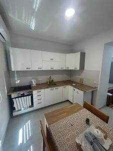 a small kitchen with white cabinets and a table at Apartmani prenj 1 i 2 centar in Konjic