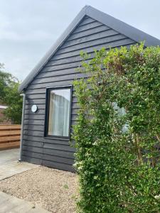 a black house with a window and a bush at NoSa Sleep, Sfeervol vakantiehuis in Grijpskerke in Grijpskerke