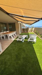 a patio with lounge chairs and a table and a lawn at La Tejita Amor by BE HAPPY Sotavento Suites New 2025 in El Médano