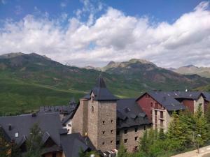 a large building with mountains in the background at Ibón de Sarrato in Formigal