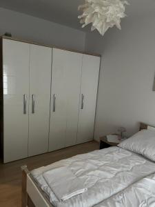 a bedroom with white cabinets and a bed and a chandelier at Apartament Polanki E207 in Kołobrzeg +6 photos