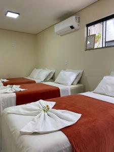 a hotel room with three beds with towels on them at Casa Temporada Espaço Vip in Barra do Garças