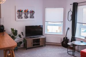 カーディフにあるCosy Stays Cardiffのリビングルーム(木製キャビネット内の薄型テレビ付)