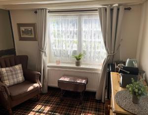 a living room with a chair and a window at Thatched Cottage Hotel in Brockenhurst