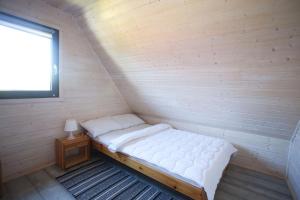 a small bed in a room with a window at Domki Tabaluga in Rusinowo +24 photos