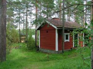 a small red house in the middle of a forest at Taivasalla glamping - luxury stay with a view to the lake in Tampere