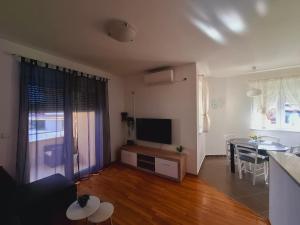 a living room with a television and a dining room at Apartment ARIELA in Tisno