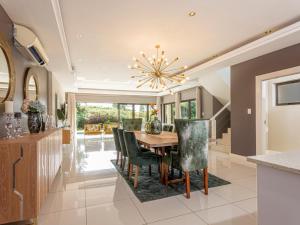 a dining room with a table and chairs and a chandelier at Corals 4, Zimbali Estate by Euphoric Leisure in Ballito