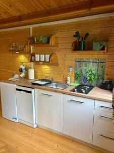 a kitchen with white cabinets and a sink at Butelkowa Zieleń in Wejsuny +45 photos