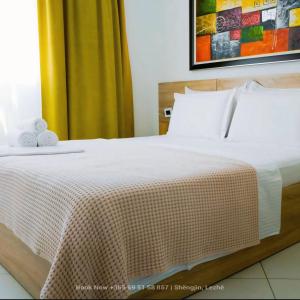una camera da letto con letto, lenzuola e cuscini bianchi di Carpe Diem Apartments-Hotel a Shëngjin