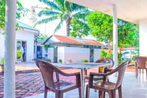 a table and chairs on a patio with palm trees at Hôtel de l'Aéroport in Brazzaville