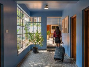 a woman walking down a hallway with a suitcase at The Hosteller Bam Goa, Saligao - Poshtel in Calangute