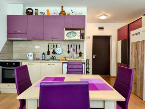 a kitchen with purple cabinets and a table and purple chairs at TihON Studio in Byala