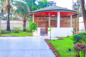 a gazebo with a red roof in a yard at Brazza Hôtel in Brazzaville