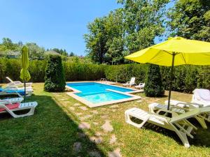 a swimming pool with chairs and an umbrella at TihON Studio in Byala