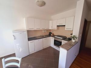 a small kitchen with white cabinets and a sink at Apartment ARIELA in Tisno