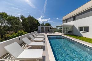 a swimming pool with lounge chairs next to a house at Alba Family Home in Zadar