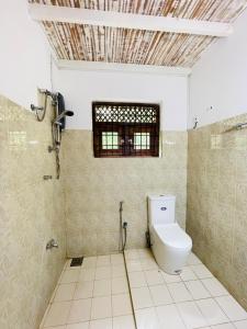 a bathroom with a toilet and a window at Marisol Villa in Unawatuna