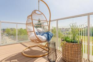 a swinging chair on a balcony with plants at POSESJA PLAŻOWA PREMIUM - Apartments & SPA in Grzybowo