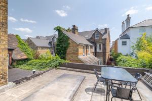 un patio con 2 sillas y una mesa en la parte superior en Kew Garden Suite 2BR Sleeps 9 Near Central London, en Richmond upon Thames