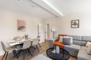 Una sala de estar con un sofá y una mesa con sillas. en Kew Garden Suite 2BR Sleeps 9 Near Central London, en Richmond upon Thames