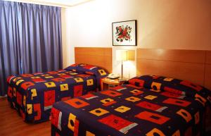 a hotel room with two beds with colorful covers at Hotel del Principado in Mexico City