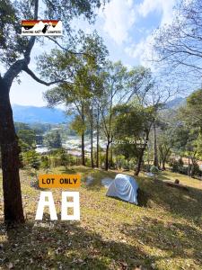 a tent in a field next to a sign at The Hunting Rat Campsite in Ban Tai