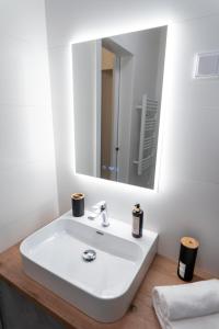 a bathroom with a white sink and a mirror at AApartman Wellness - Privát Spa élmény - Bor bekészítéssel in Pécs