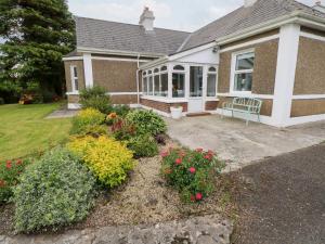 a house with a porch and flowers in the yard at Churchfield House in Ballina