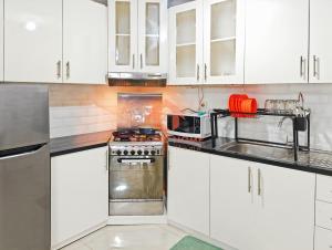 ジャカルタにあるLarge 3BR Rasuna Apt with Pool, Gym, WiFi by 2ndHomeの白いキャビネットとコンロ付きオーブンを備えたキッチン