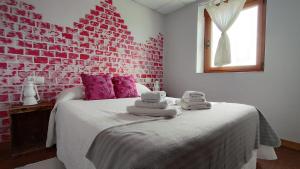 a bedroom with a brick wall and a bed with towels on it at Casa rural Julia in Olleros de Tera