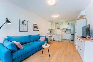 a living room with a blue couch and a kitchen at Flex SelfCheckIns 149 - Zagreb - Bedroom - Garage - Loggia in Zagreb