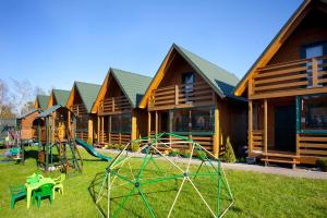 a group of houses with a playground in the yard at Domki Tabaluga in Rusinowo