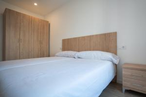 a bedroom with a large white bed and wooden cabinets at LETS HOLIDAYS Centric & Near the Sea Victoria apartment 3 in Tossa de Mar