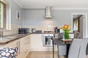 a kitchen with white cabinets and a table with a vase of flowers at The Willows - Peaceful Retreat in Saundersfoot +12 photos