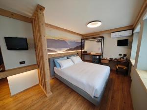 a bedroom with a large white bed and a television at Da Gigi Alpine Rooms in Crandola Valsassina