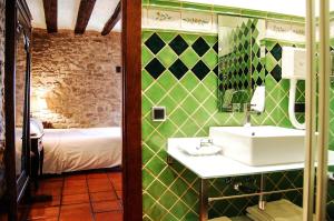 Un baño con lavabo y una cama en una habitación. en Hotel Rural Nobles de Navarra, en Áibar