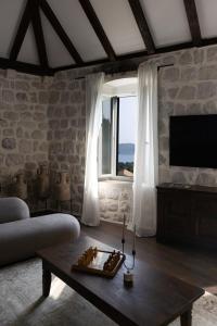 a living room with a couch and a table and a window at Heritage house Stone Orchard, near Dubrovnik in Orasac