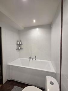a white bathroom with a tub and a toilet at Key to Jurmala in Jūrmala